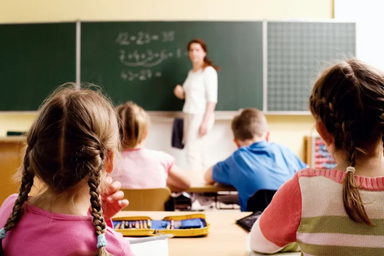 A teacher stands at a chalk board in front of students