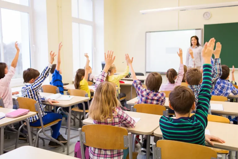 Students raise their hands to answer a teacher